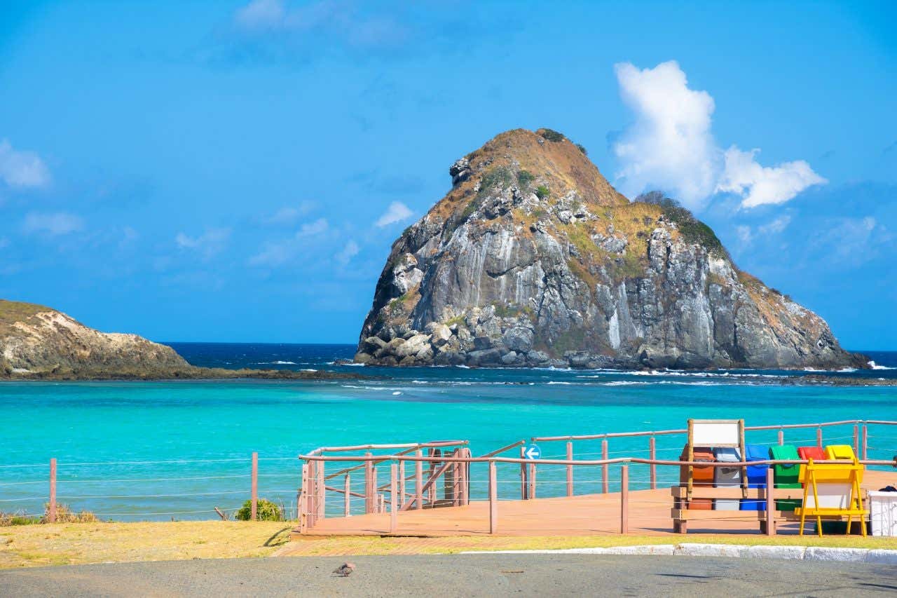 Vista panorâmica do mar turquesa com um grande morro ao fundo