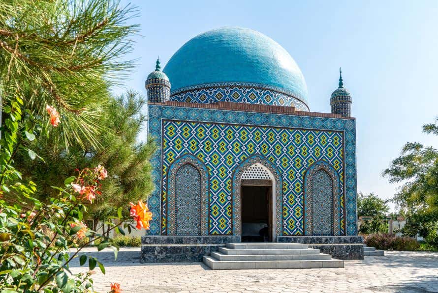 A view of a blue domed building with tiles all over it under a clear blue sky, in the Fergana Valley in Uzbekistan.