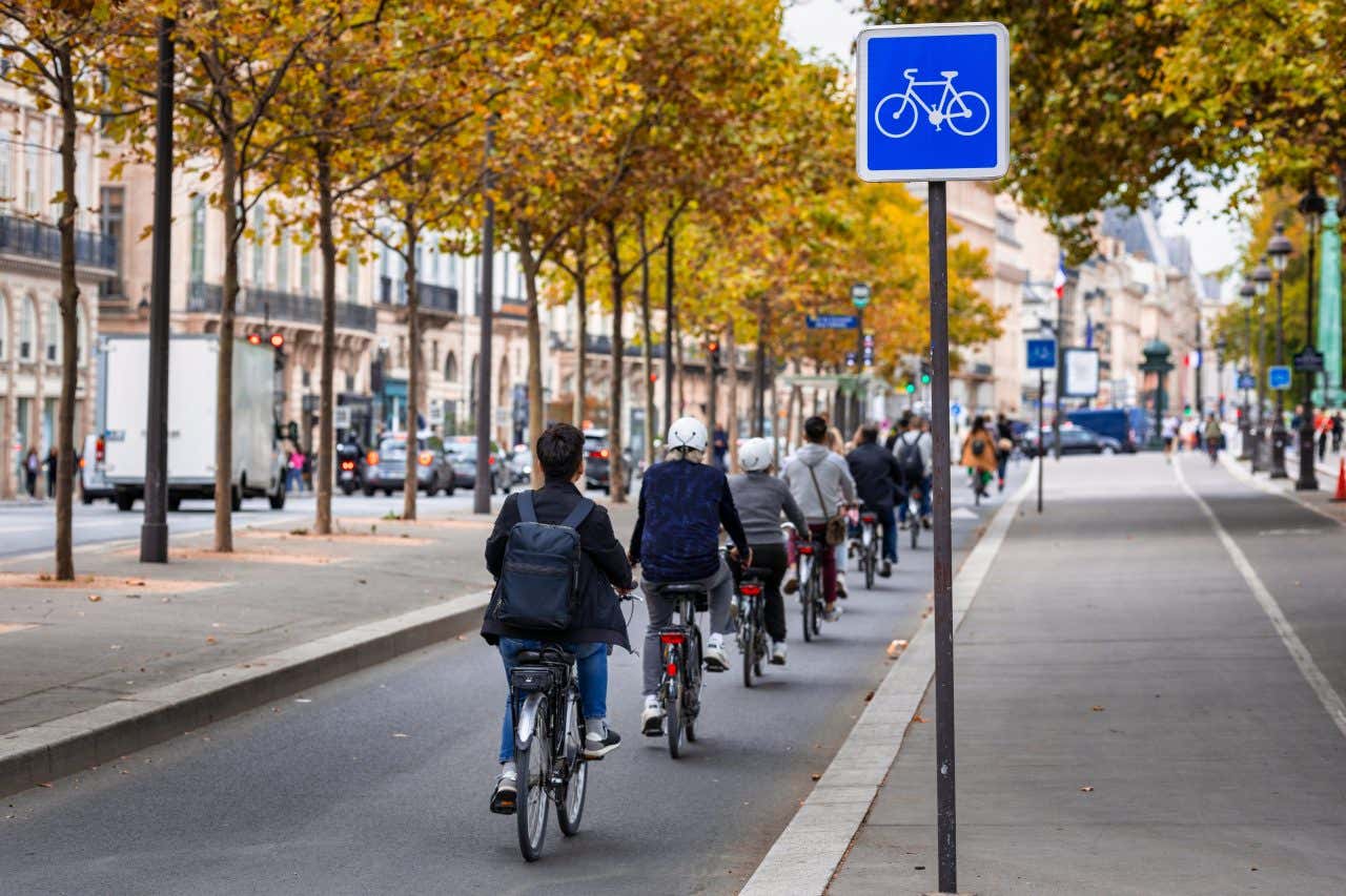 A line of commuters bike down a bike path in Paris, France on a cloudy autumn day, now one of the top cycling cities with separated bike paths