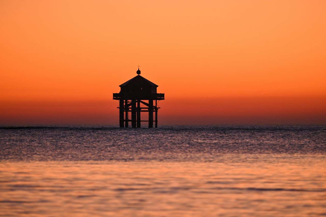Phare du Bout du Monde au coucher du soleil, avec le ciel rose orangé