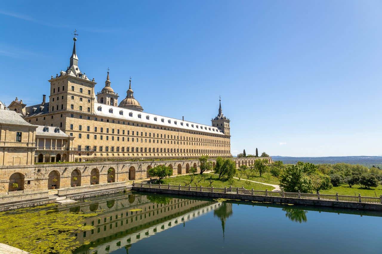 Vue en angle du Monastère Royal de l'Escurial dans la Communauté de Madrid, un site de l'UNESCO, le bassin de réflexion reflétant un ciel clair au-dessus