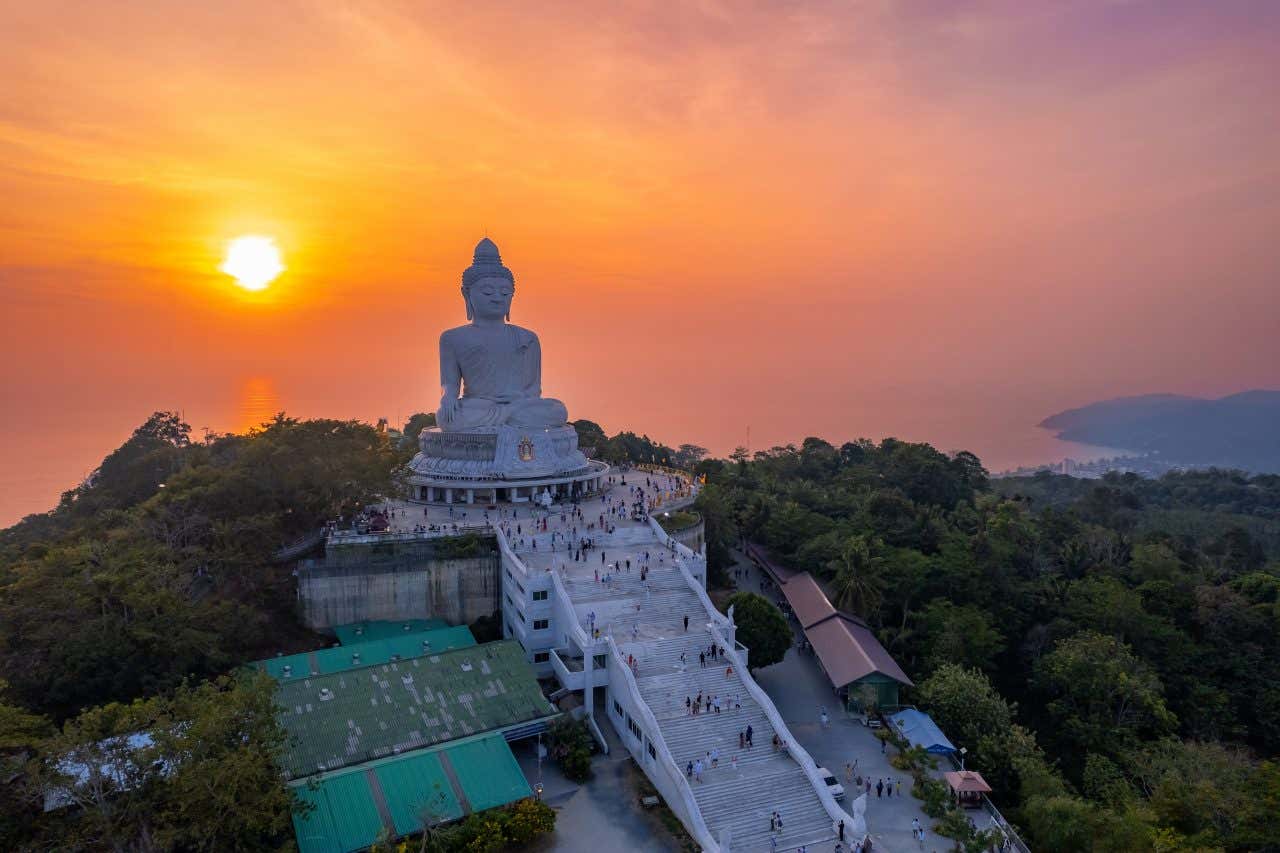 A large Buddha statue in Phuket at sunset.