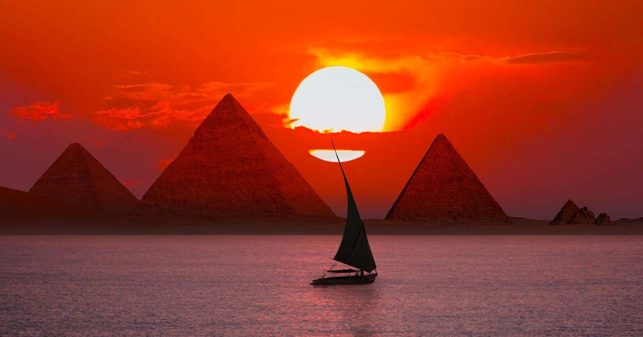 Bateau sur le Nil au coucher du soleil avec des pyramides en arrière-plan