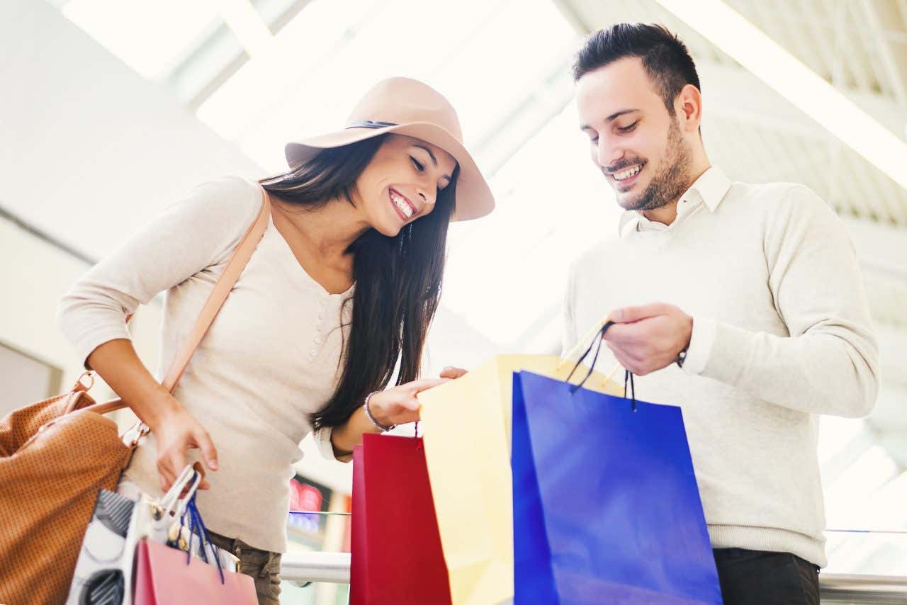 Um casal repleto de sacolas de compras em um centro comercial