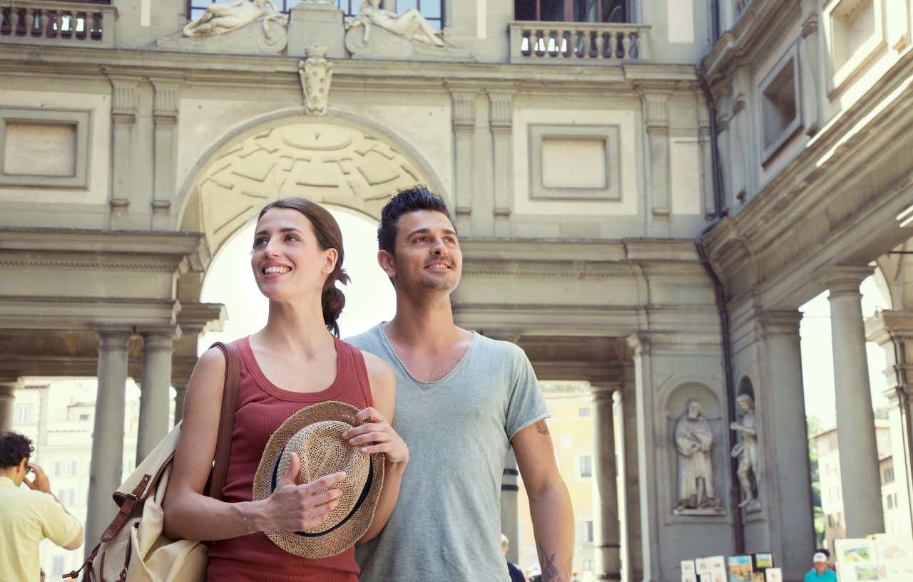 Una ragazza e un ragazzo osservano il chiostro della Galleria degli Uffizi a Firenze in una calda giornata estiva