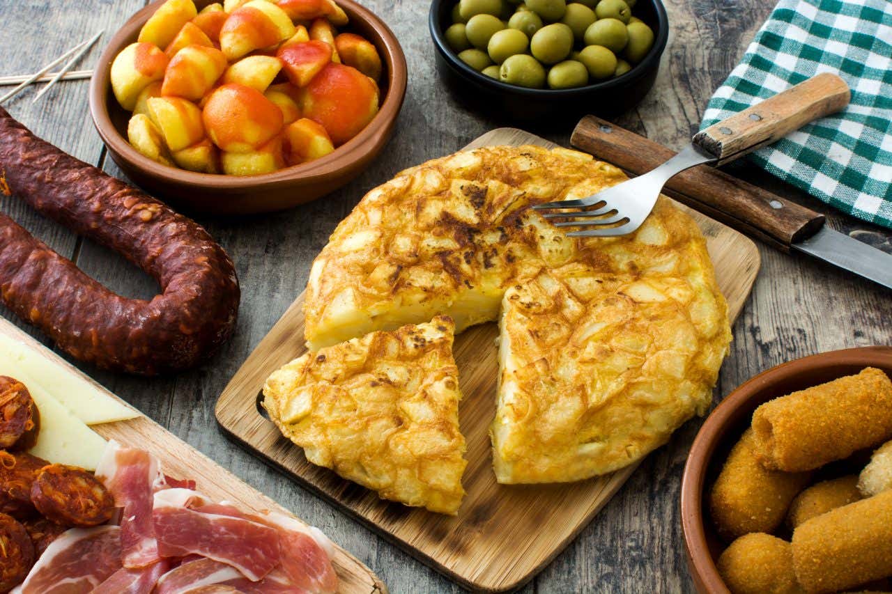 Une table avec des spécialités espagnoles comme la tortilla, les croquetas, les patatas bravas et la charcuterie ibérique