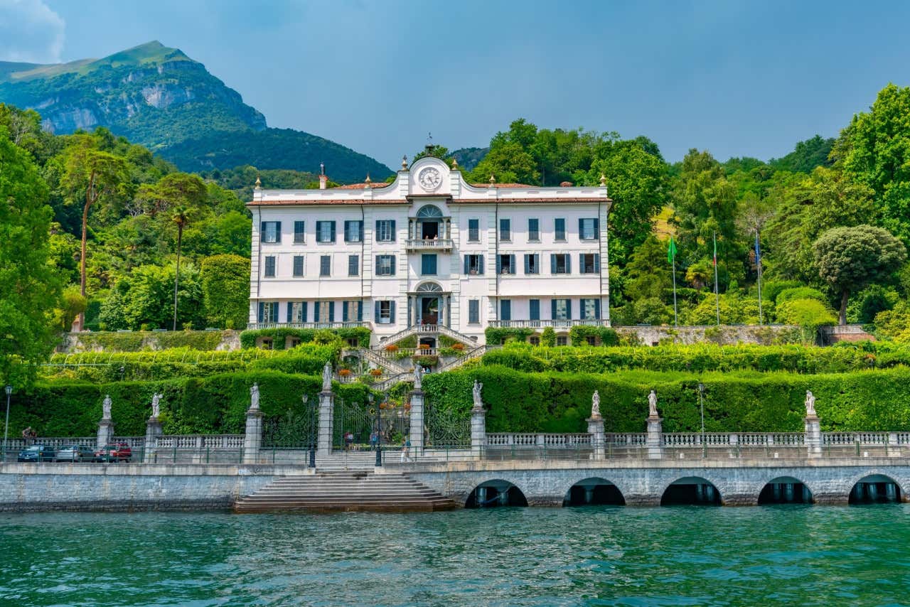 Villa neoclásica italiana ubicada a la orilla del Lago de Como, rodeada de una densa vegetación, un día soleado
