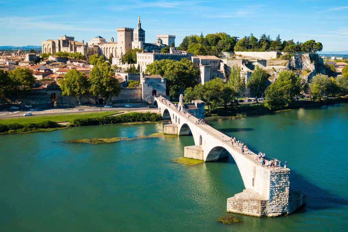 Vista aérea de una ciudad medieval, con un puente de piedra en primer plano cruzando un río (el puente está incompleto)