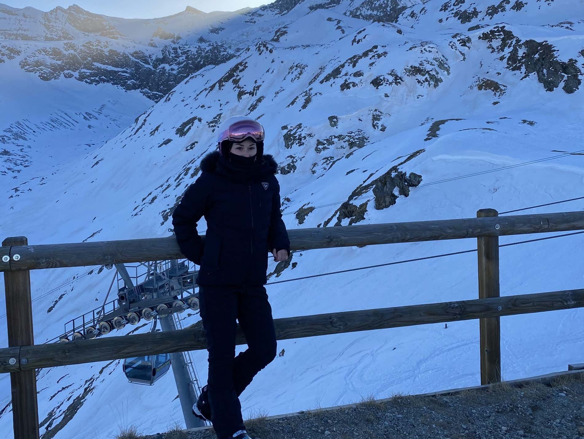 Una mujer vestida con ropa de nieve posando para una foto junto a un paisaje nevado