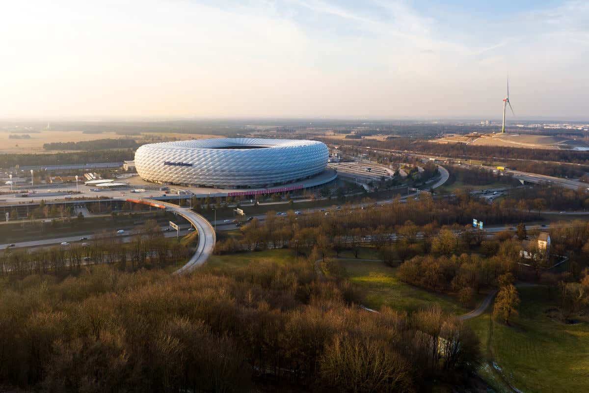 Un estadio de fútbol de aspecto vanguardista rodeado de carreteras, árboles e, incluso, un moderno molino de viento
