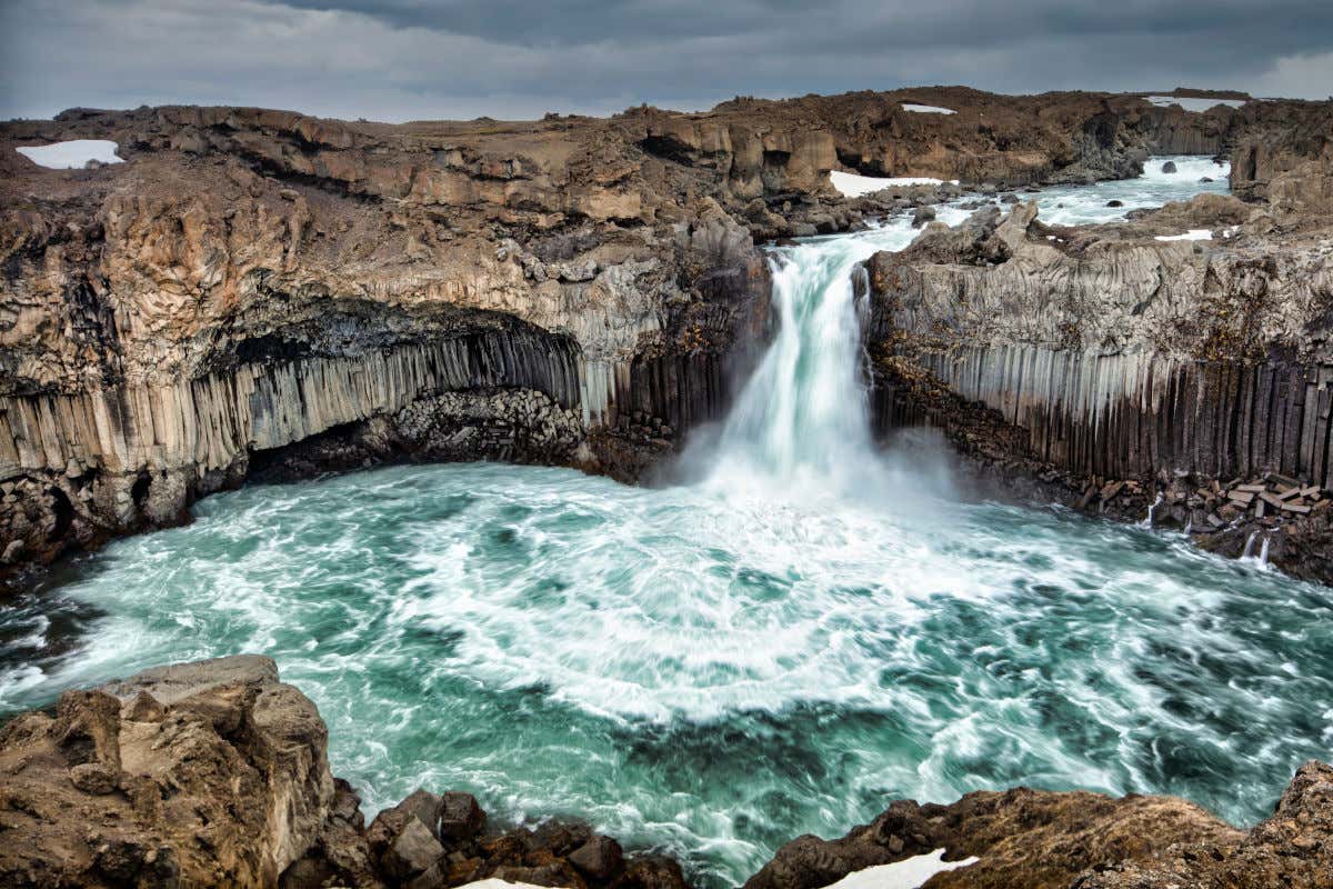Una cascada cayendo al mar entre impresionantes paredes de piedra negra volcánica