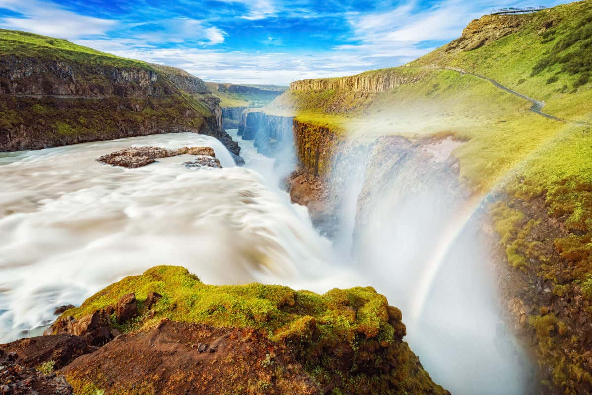 Una cascada cayendo en un profundo desfiladero y formando un arcoíris