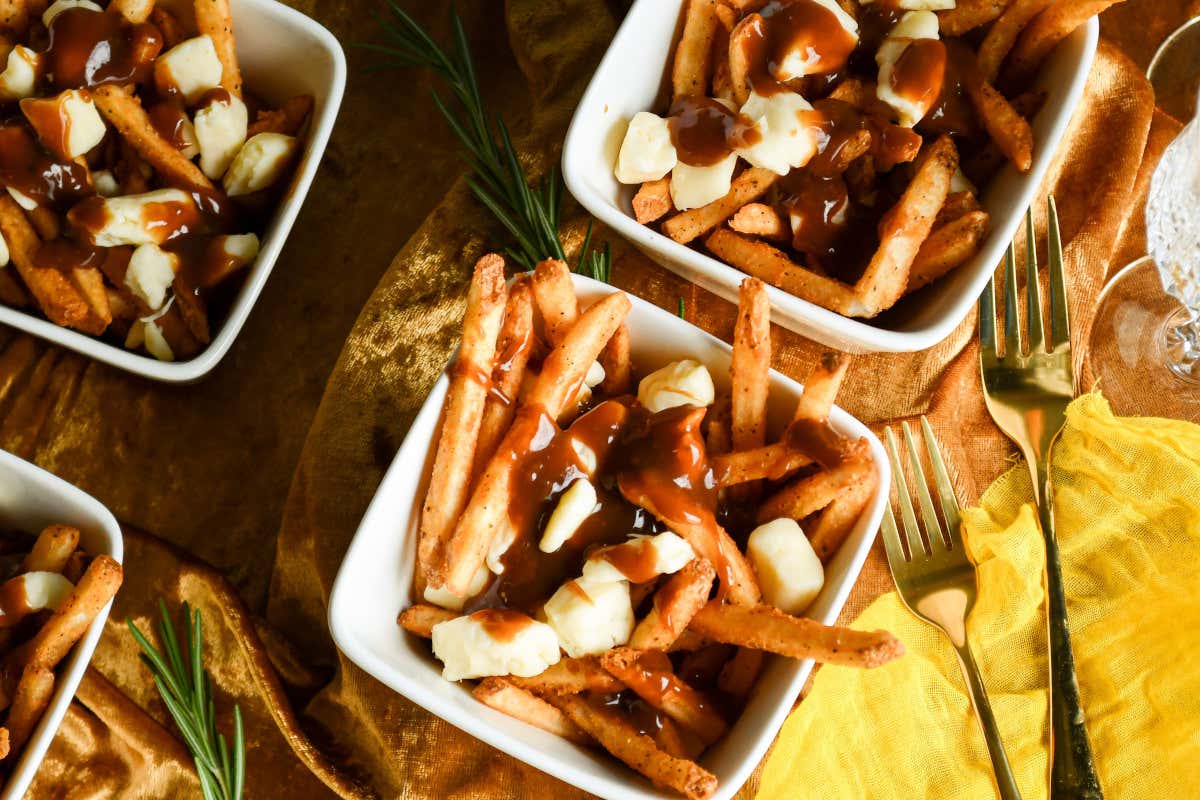 Detalle de un plato de patatas fritas sazonado con distintas salsas