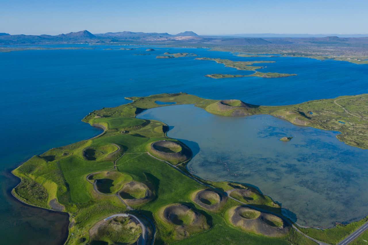 Vista aérea de un lago de Islandia rodeado de pequeños conos volcánicos