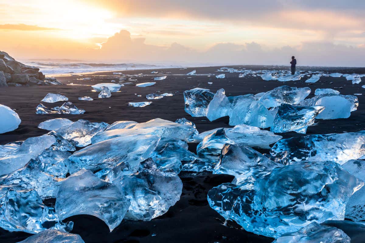 Pequeños bloques de hielo de color azulado contrastando con la arena negra de una playa de Islandia