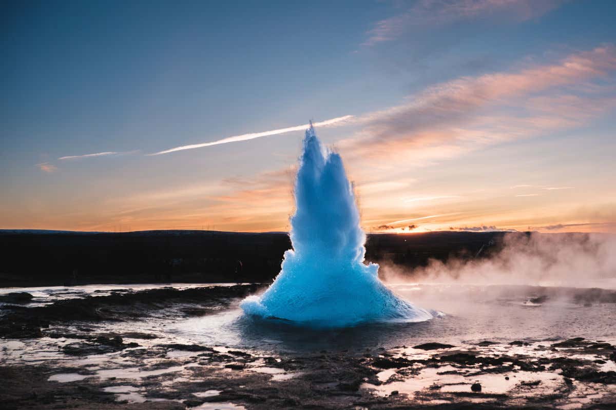 Un géiser expulsando agua hirviendo al atardecer