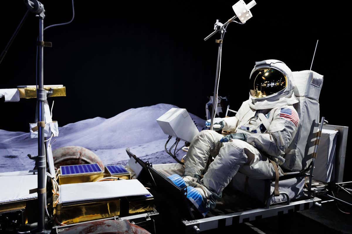 Un traje de astronauta con bandera americana y junto a un robot espacial en el interior de un museo