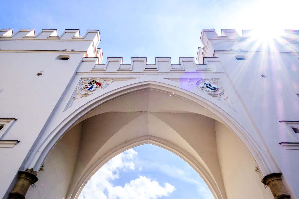 Una antigua puerta medieval decorada con escudos y pintada de blanco