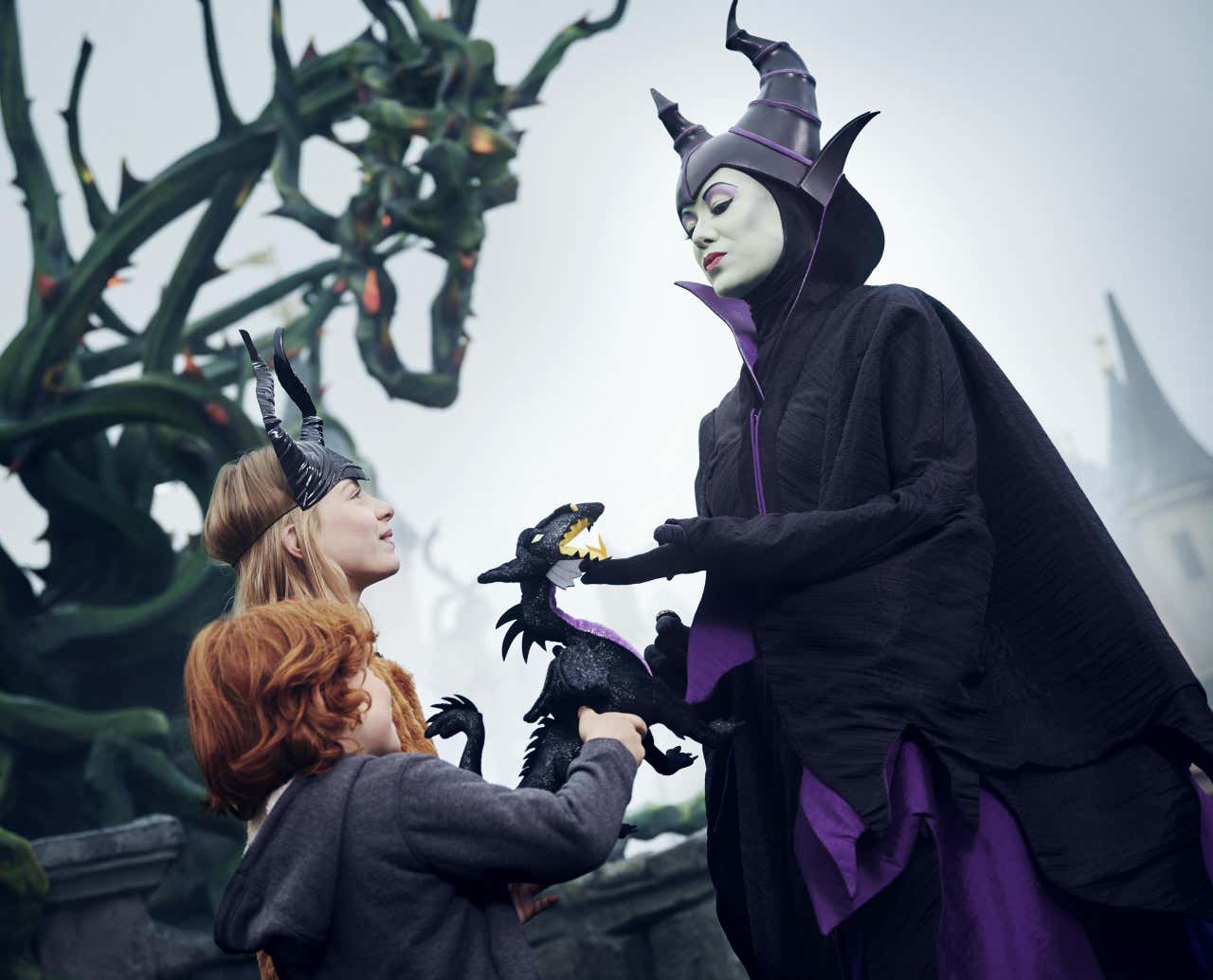 Duas crianças fantasiadas para o Halloween ao lado da Maléfica na Disneyland Paris