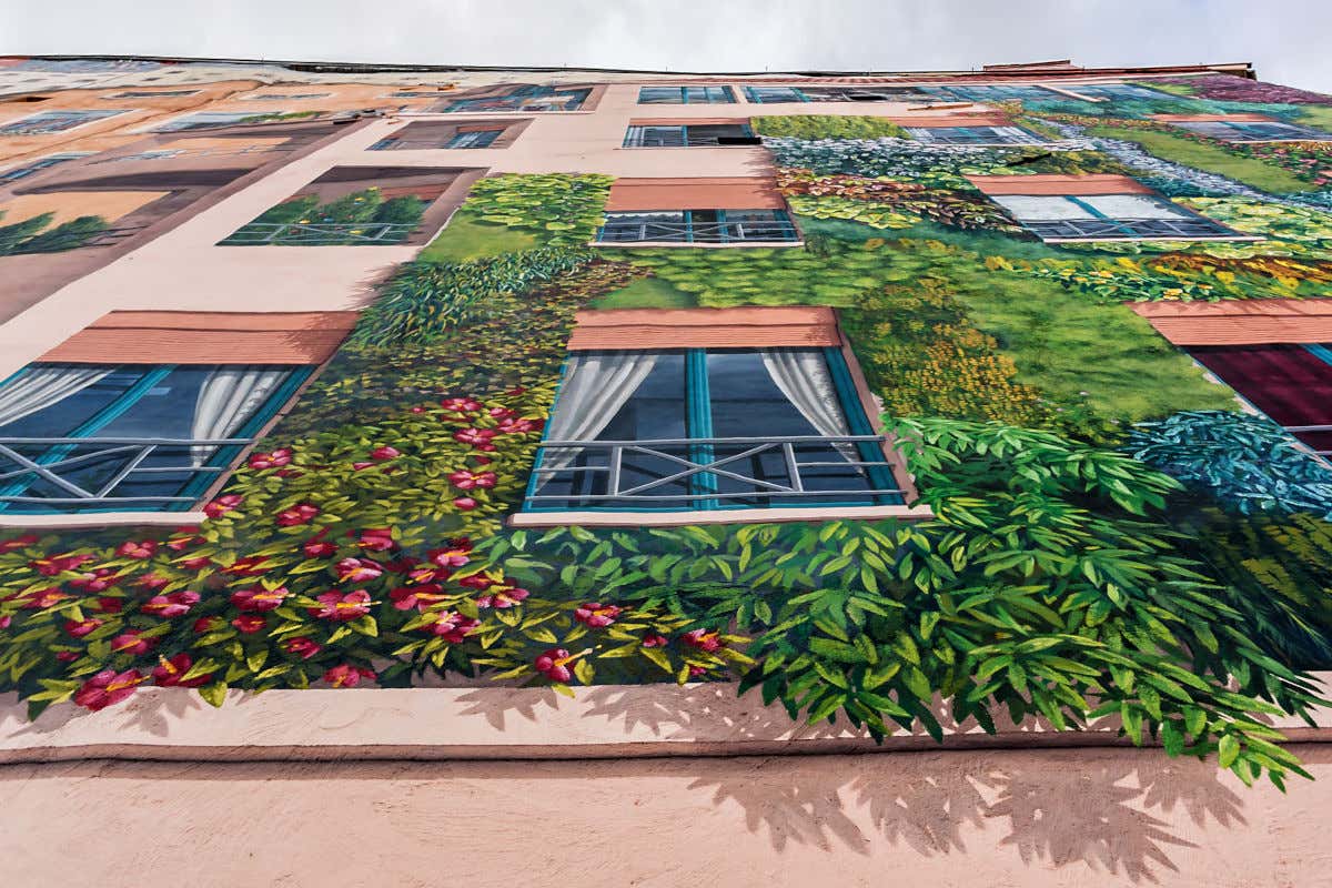 Un edificio con ventanas y plantas falsas recreadas con pintura como una obra de arte urbano