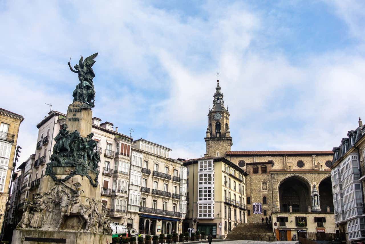 Panorámica de la plaza de la Virgen Blanca en Vitoria con una escultura en un lateral y el cielo nuboso