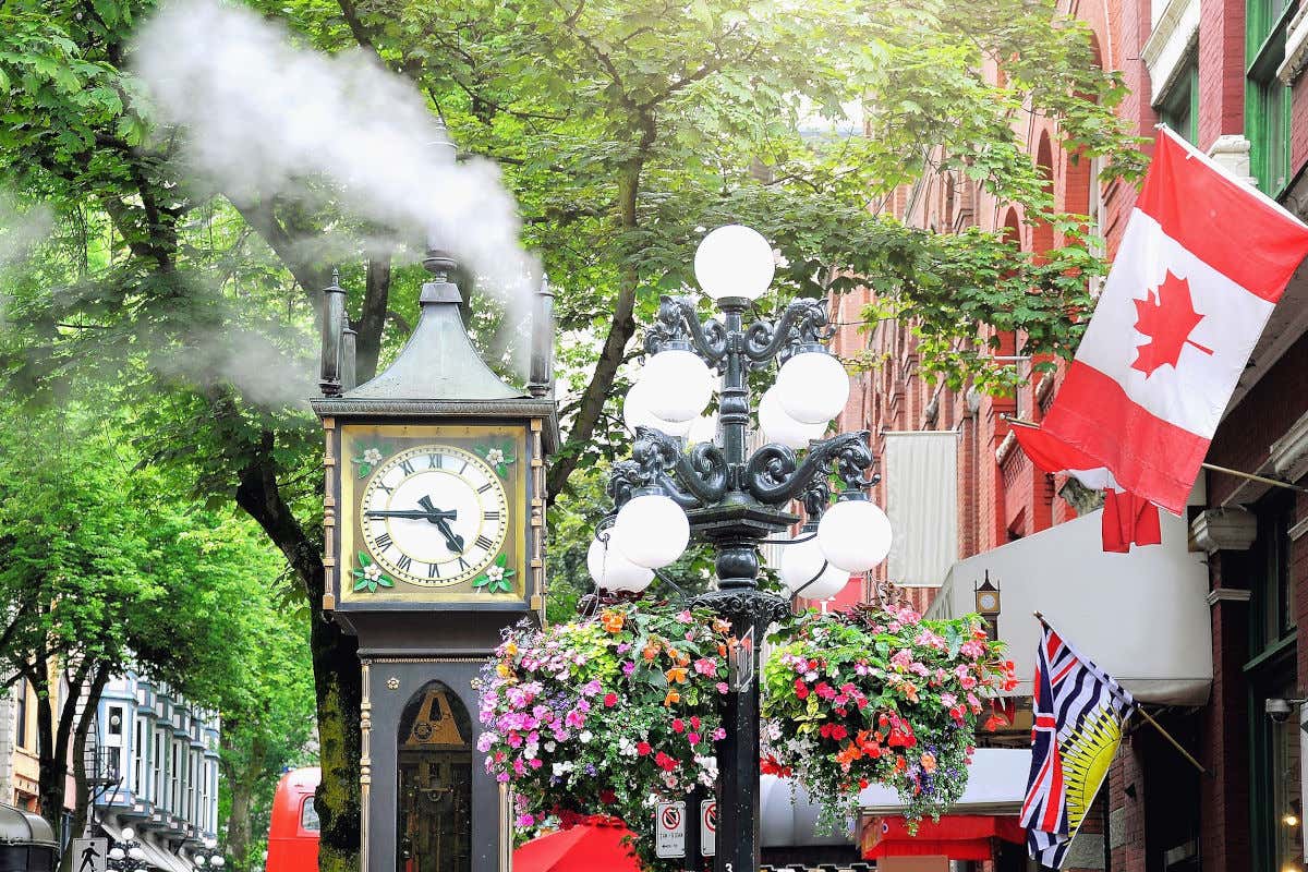 Reloj de vapor emitiendo humo, junto a una bandera de Canadá en el edificio anexo