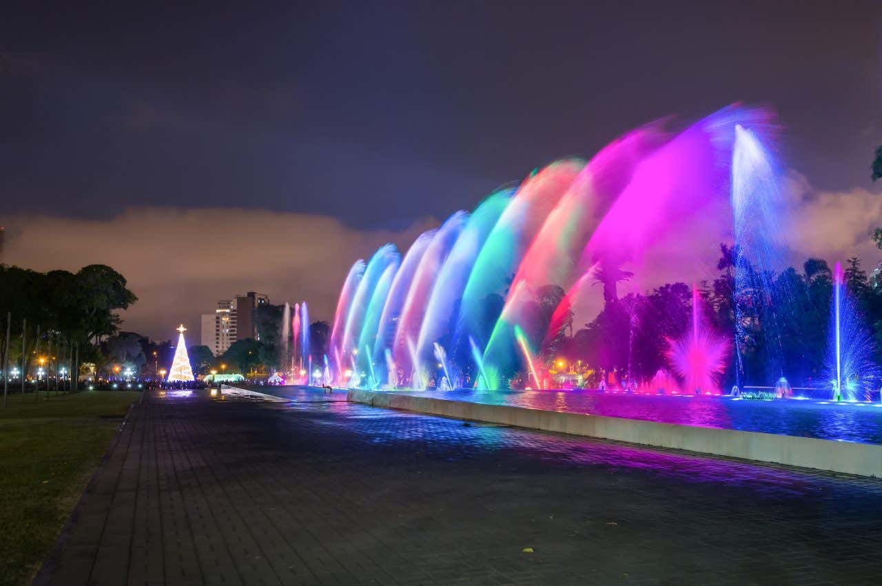 Jatos de água iluminados com luzes coloridas em uma esplanada de Lima