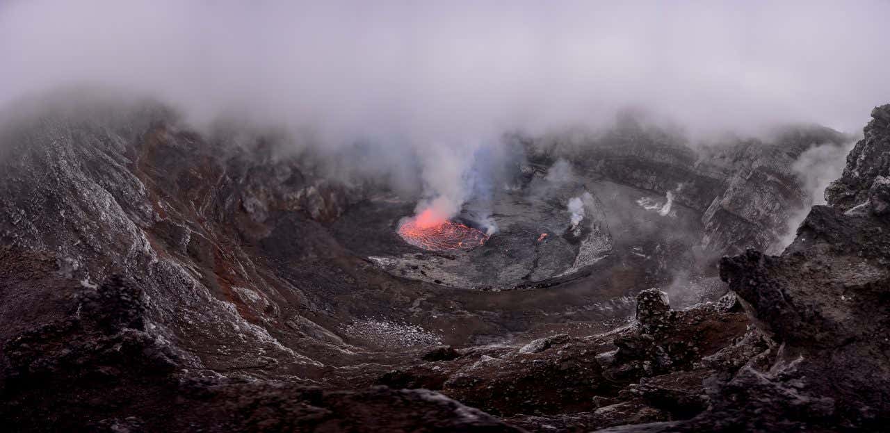 Vista dall’alto del cratere del vulcano Nyiragongo, avvolto da fumi e vapori, con un piccolo lago di lava incandescente al centro