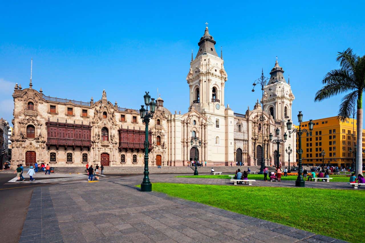 Catedral de Lima em frente à Plaza Mayor com pessoas sentadas nos bancos da praça