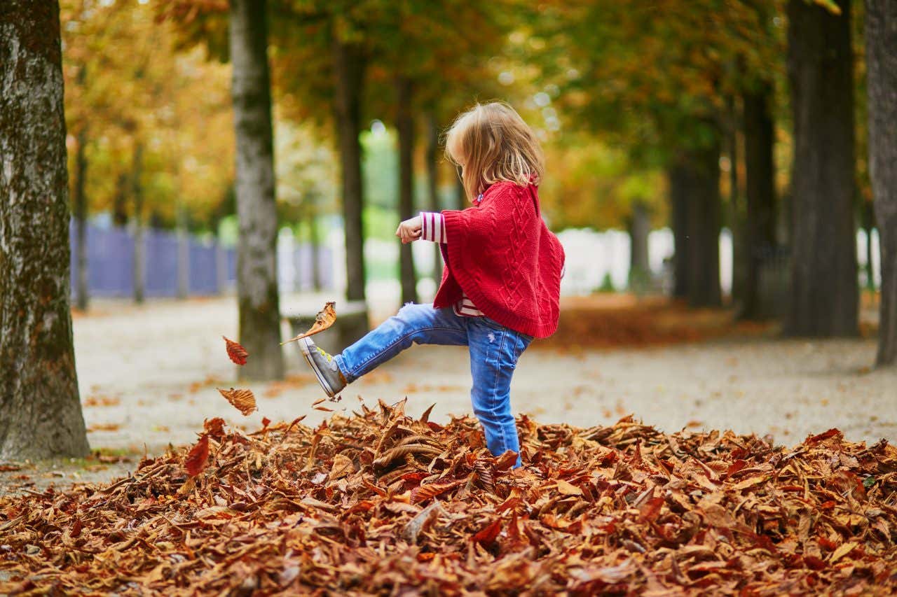 Un enfant à Paris en automne, jouant dans les feuilles mortes
