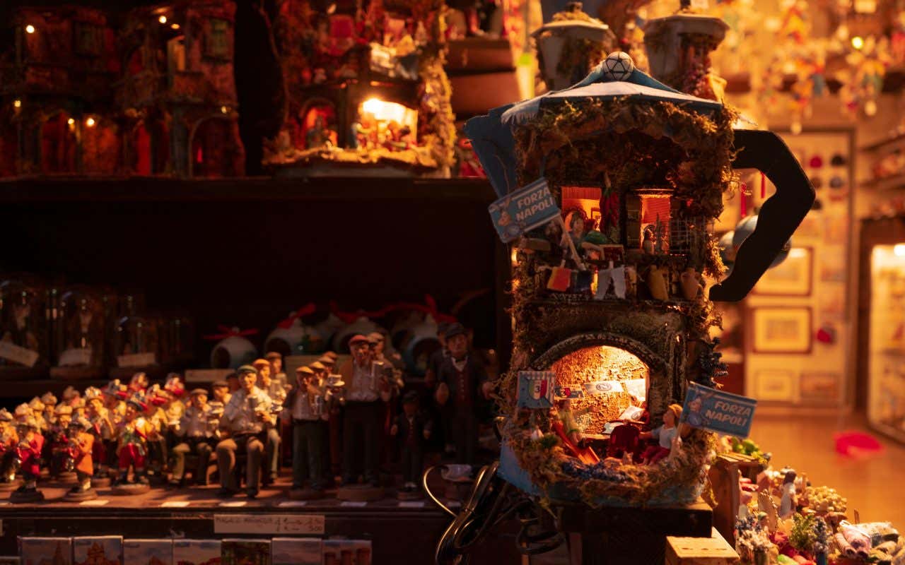 Vetrina di una bottega artigianale a San Gregorio Armeno, Napoli, con presepi tradizionali illuminati e statuine esposte