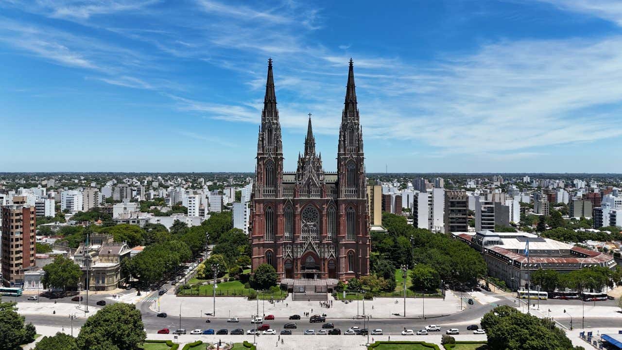 The Cathedral of La Plata seen from across the road up in the air, with a cloudy blue sky in the background.