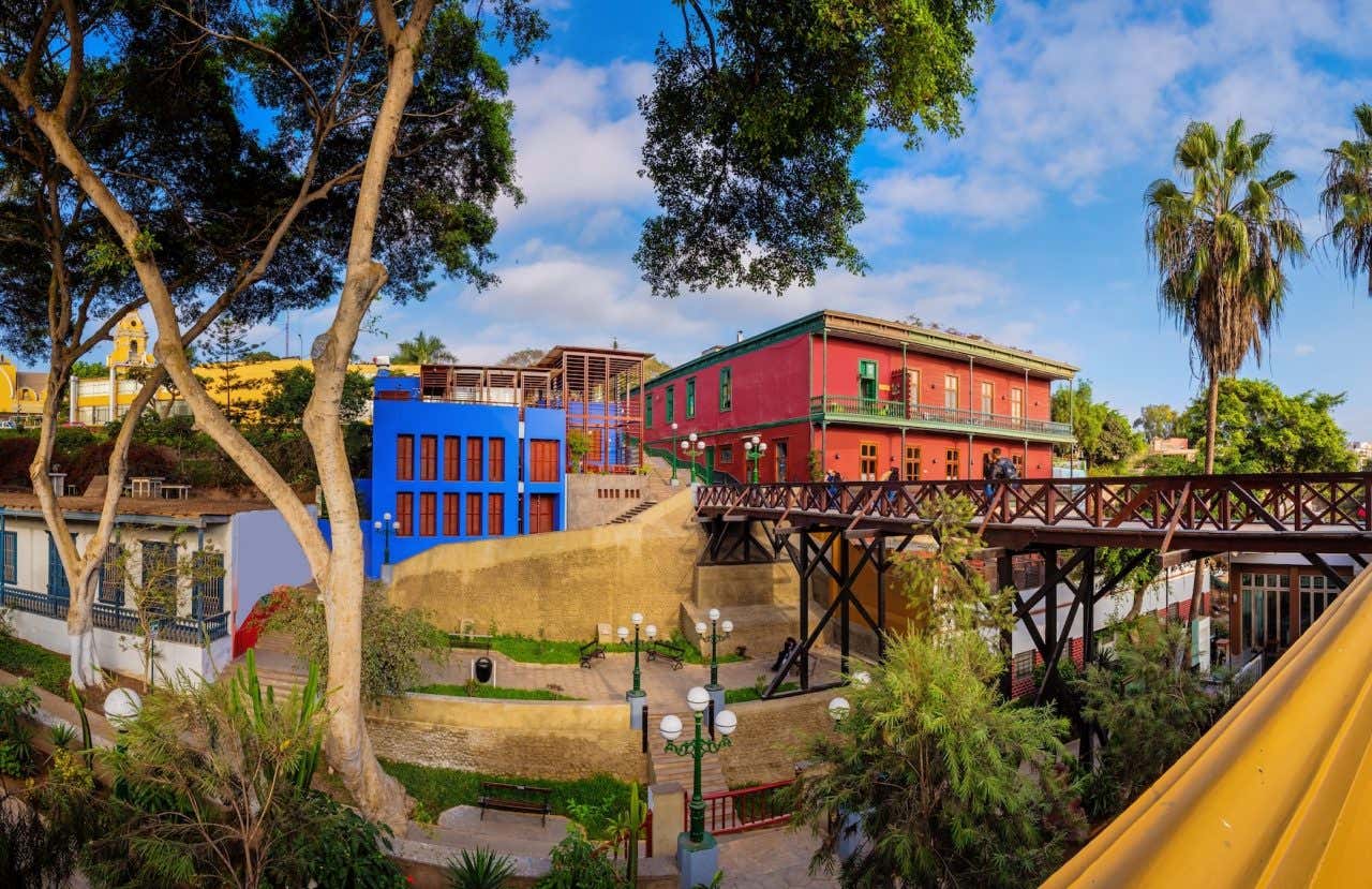 Casas coloridas em Barranco e uma passarela de madeira, rodeadas de árvores e postes de iluminação