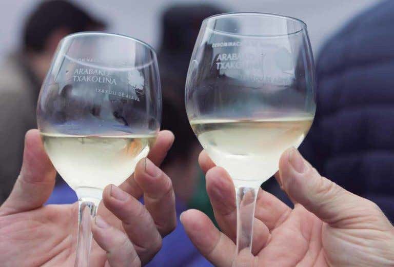 Dos manos sujetando unas copas de txakoli, bebida típica de Álava tierra de vinos