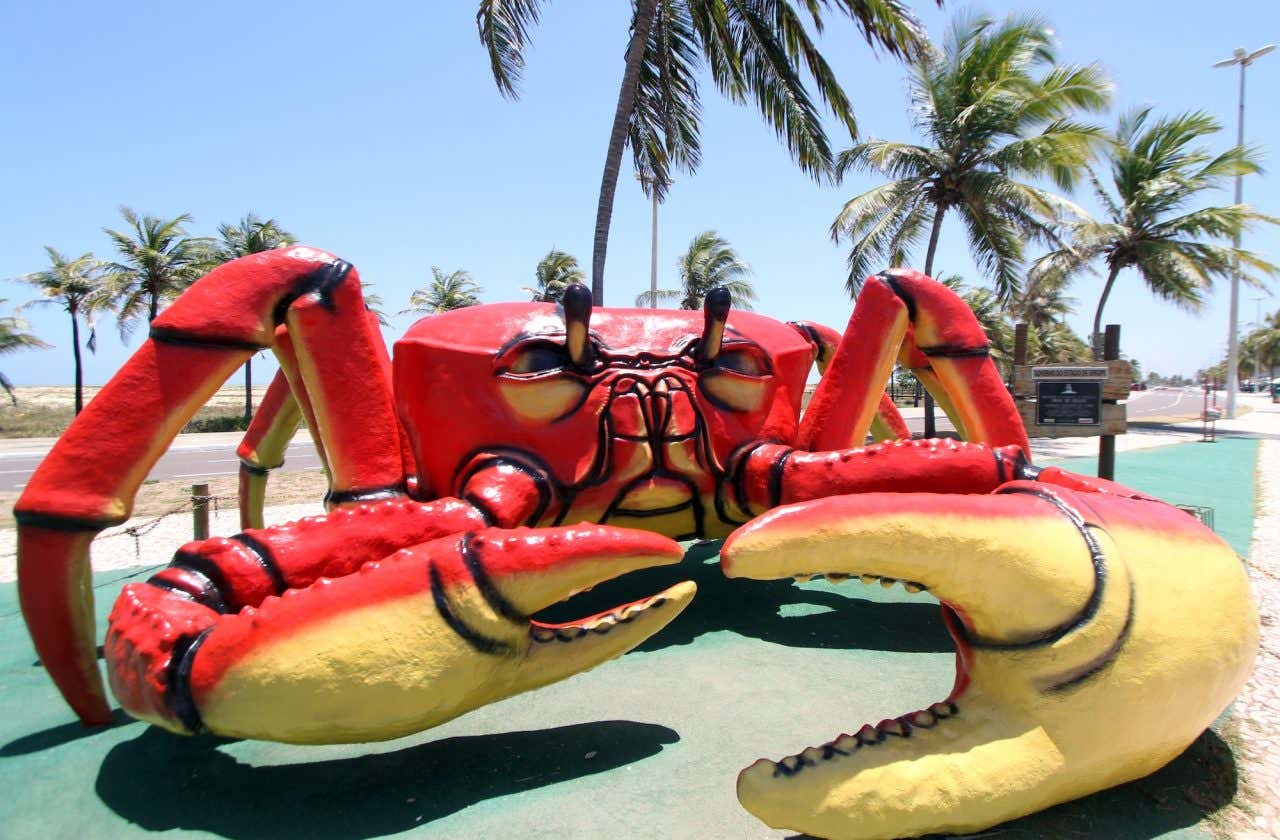 Uma grande escultura de caranguejo pintado de vermelho e amarelo, na Orla de Atalaia