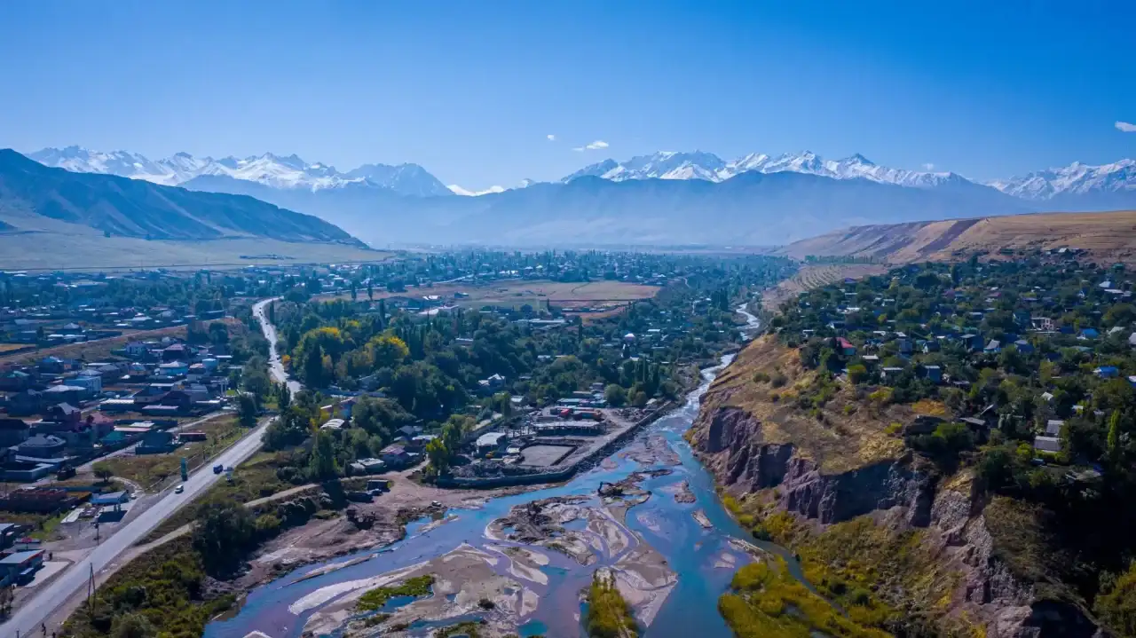 Vista panorâmica da cidade de Bishkek, capital do Quirguistão, com montanhas, vegetação e um rio