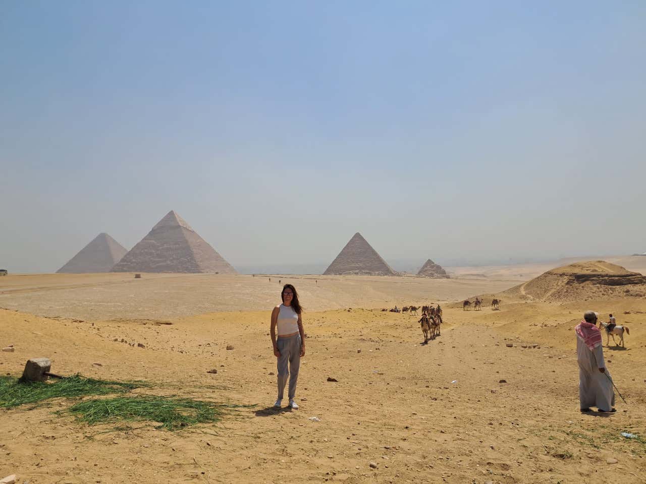 Una mujer posando con las pirámides Giza al fondo, en Egipto
