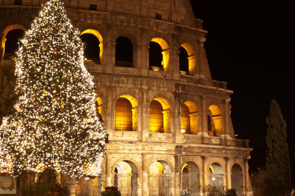 Un árbol de Navidad iluminado por la noche junto al Coliseo de Roma