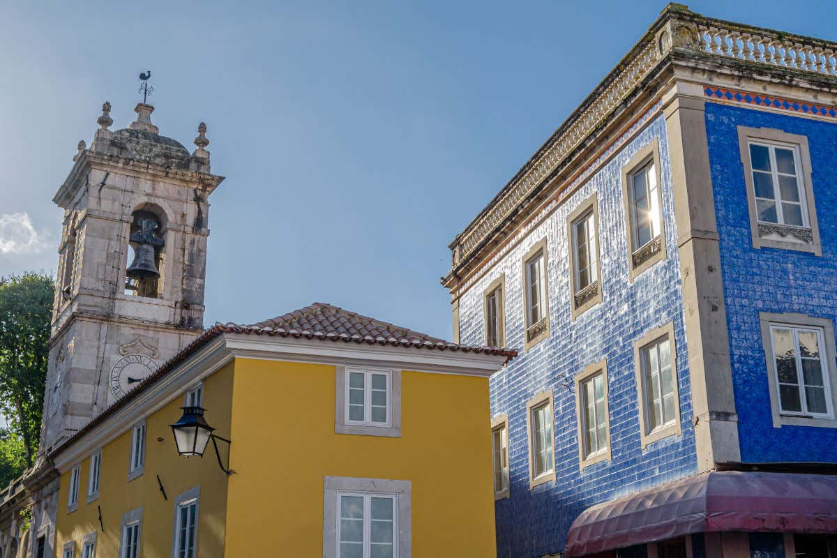 Varios edificios coloridos y de pequeño tamaño junto a la torre-campanario de una iglesia de Sintra