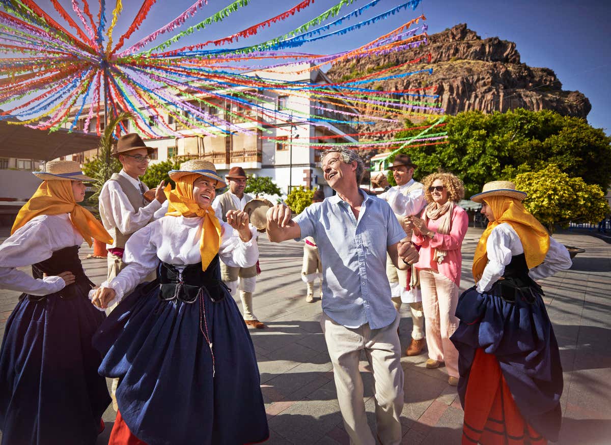 Varias personas bailando y cantando en una plaza de un municipio de La Gomera