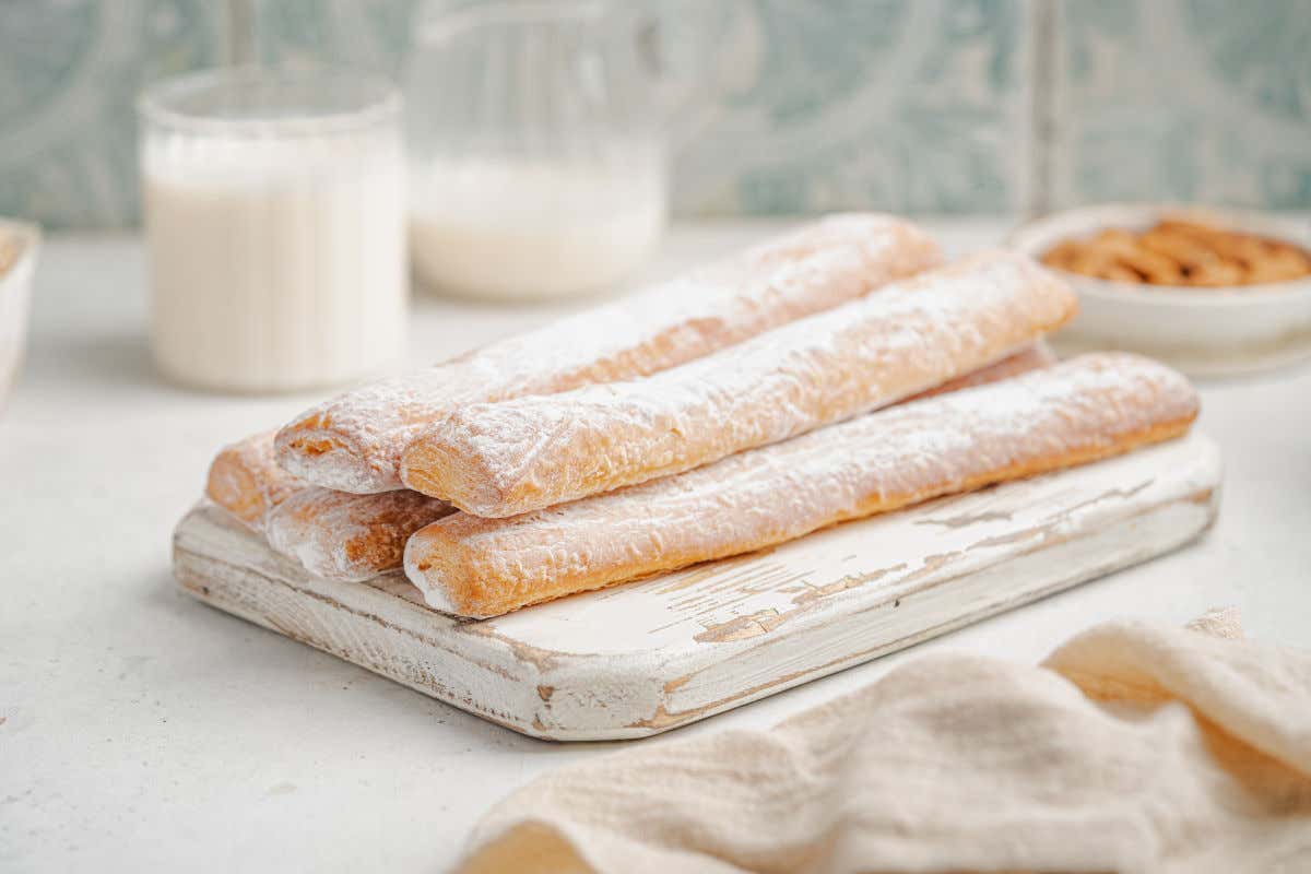Una mesa blanca con varias tiras de hojaldre típicas de Valencia, conocidas como fartons, y varios vasos de horchata