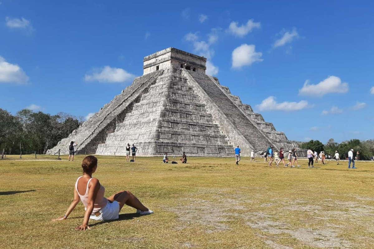 Una chica sentada mirando la pirámide de Chichen Itza en un día despejado