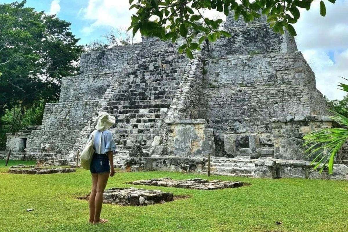 Una chica con sombrero y ropa de verano viendo una antigua pirámide maya