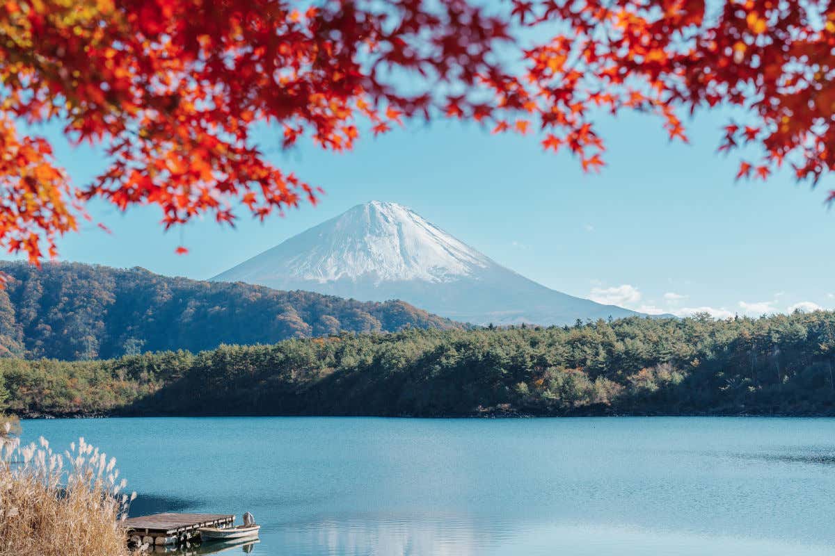 Panorámica del monte Fuji nevado detrás de unas montañas y un lago de aguas cristalinas