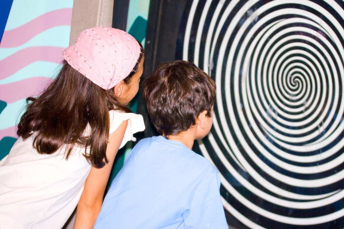 Dos niños contemplando un disco giratorio que genera un curioso efecto óptico