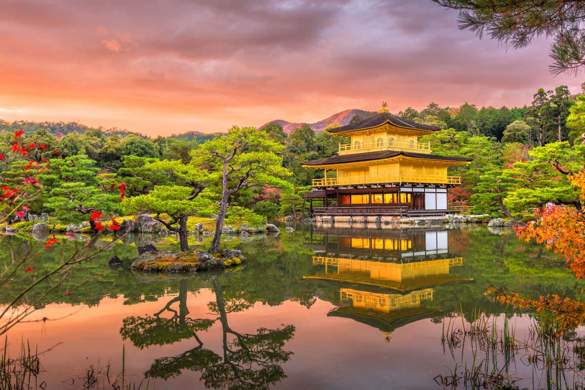 Un templo de color dorado en mitad de un lago y rodeado de un frondoso bosque al atardecer