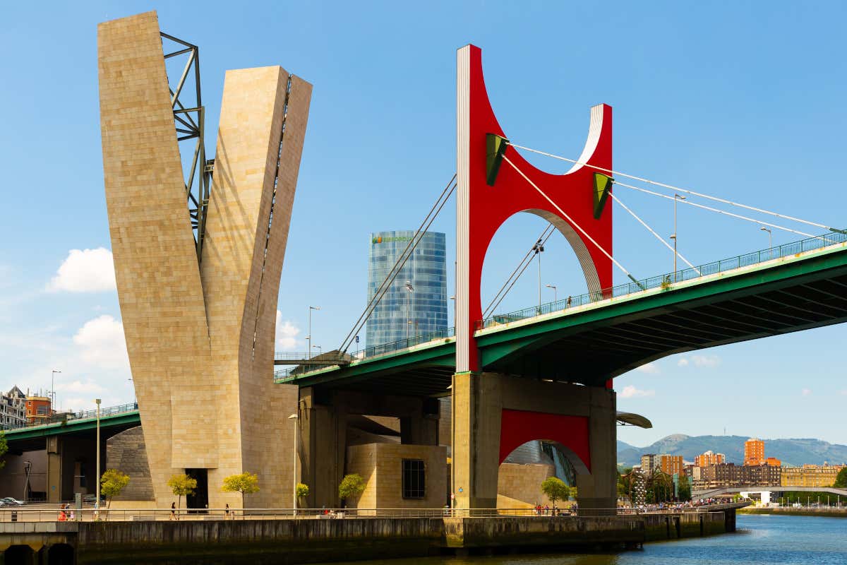 Detalle de un arco de color rojo sobre un puente que cruza un río
