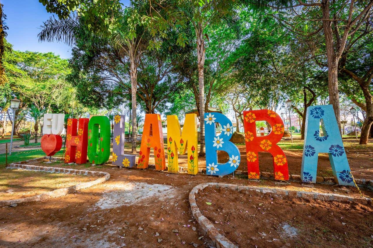 Um letreiro colorido com flores pintadas escrito Eu Amo Holambra em um parque natural