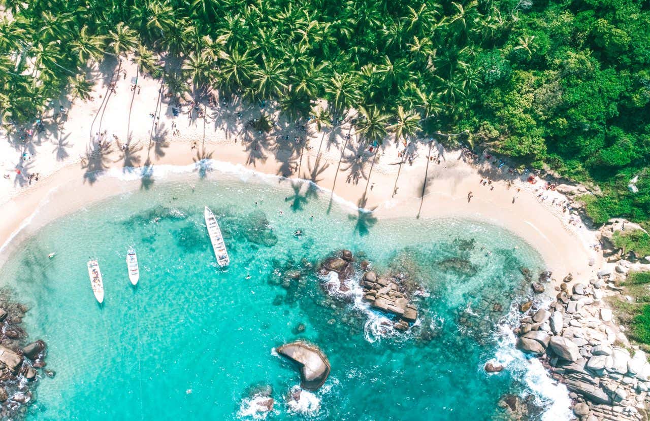 Vue aérienne d'une plage turquoise au sable blanc et d'une jungle verdoyante au Parc de Tayrona, à faire en Colombie