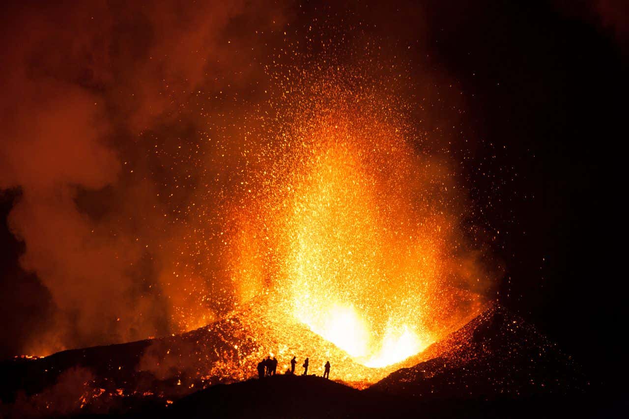 Magma do vulcão Eyjafjallajökull jorrando com força durante a noite diante de alguns espectadores.